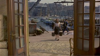 Movie still from “Fanny” (1961), directed by Joshua Logan – A woman carrying a basket walks down the street; Wide shot, High angle