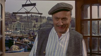 Movie still from “Fanny” (1961), directed by Joshua Logan – An older man wearing a hat and a striped shirt; Medium shot, High angle