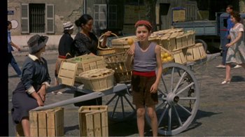 Movie still from “Fanny” (1961), directed by Joshua Logan – A boy standing in front of a wagon filled with baskets; Wide shot, High angle