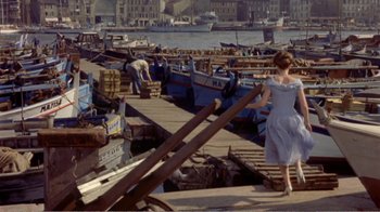 Movie still from “Fanny” (1961), directed by Joshua Logan – A woman in a blue dress walking down a pier; Wide shot, High angle