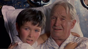 Movie still from “Fanny” (1961), directed by Joshua Logan – An older man and a young boy laying in a bed; Close Up shot, High angle