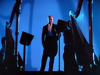 Movie still from “Fantasia” (1940), directed by Ford Beebe Jr. – A man standing in front of a bunch of musical instruments; Wide shot, Low angle