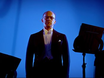Movie still from “Fantasia” (1940), directed by Ford Beebe Jr. – A man in a suit standing in front of a microphone; Medium shot, Low angle