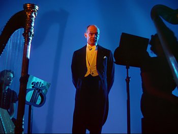 Movie still from “Fantasia” (1940), directed by Ford Beebe Jr. – A man in a tuxedo standing in front of a microphone; Medium shot, Low angle