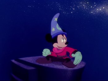 Movie still from “Fantasia” (1940), directed by Ford Beebe Jr. – A mickey mouse wearing a wizard's hat and sitting on top of a platform; Wide shot, Low angle