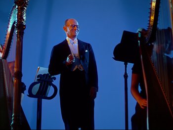Movie still from “Fantasia” (1940), directed by Ford Beebe Jr. – A man in a tuxedo standing in front of a microphone; Medium shot, Low angle