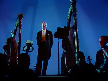 Movie still from “Fantasia” (1940), directed by Ford Beebe Jr. – A man standing in front of a group of instruments; Wide shot, Low angle