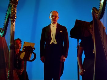 Movie still from “Fantasia” (1940), directed by Ford Beebe Jr. – A man in a tuxedo standing in front of a microphone; Wide shot, Low angle
