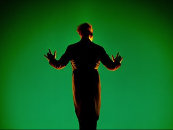 Movie still from “Fantasia” (1940), directed by Ford Beebe Jr. – A person standing in front of a green background; Medium shot, Low angle