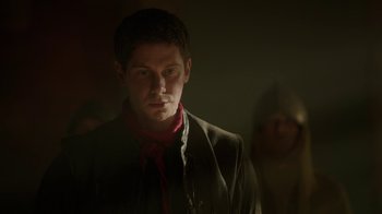 Movie still from “Game of Thrones” (2011), created by D.B. Weiss – A man in a dark room with a red scarf; Close Up shot, Over the shoulder angle