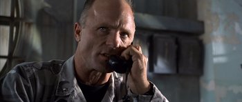 Movie still from “The Rock” (1996), directed by Michael Bay – A man talking on a phone while wearing a shirt; Close Up shot, Low angle