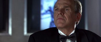 Movie still from “The Rock” (1996), directed by Michael Bay – An older man in a suit and bow tie looking up; Close Up shot, Low angle
