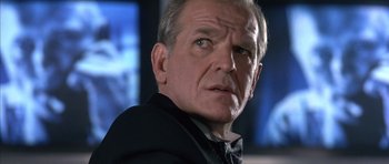 Movie still from “The Rock” (1996), directed by Michael Bay – An older man in a suit and tie looking at the camera; Close Up shot, Low angle