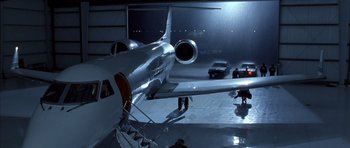 Movie still from “The Rock” (1996), directed by Michael Bay – A jet airplane parked in a hangar at an airport; Extreme Wide shot, Low angle