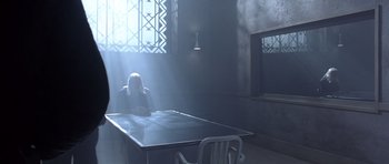 Movie still from “The Rock” (1996), directed by Michael Bay – A person sitting at a table in a room; Wide shot, High angle