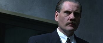 Movie still from “The Rock” (1996), directed by Michael Bay – A person wearing a suit and tie; Close Up shot, Over the shoulder angle