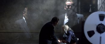 Movie still from “The Rock” (1996), directed by Michael Bay – A man and a woman sitting in front of a wall; Medium shot, Over the shoulder angle