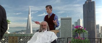 Movie still from “The Rock” (1996), directed by Michael Bay – A man sitting in front of another man in a barber chair; Medium shot, Over the shoulder angle