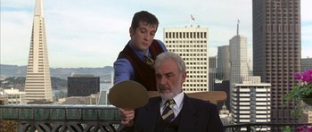 Movie still from “The Rock” (1996), directed by Michael Bay – A man in a business suit and a man in a suit and tie; Medium shot, Over the shoulder angle