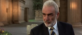 Movie still from “The Rock” (1996), directed by Michael Bay – An older man in a black suit and a yellow tie; Close Up shot, Low angle