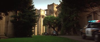 Movie still from “The Rock” (1996), directed by Michael Bay – A couple of cars parked in front of a large building; Extreme Wide shot, Low angle