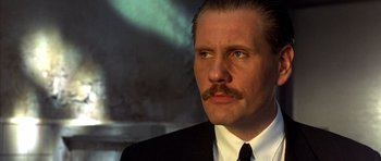 Movie still from “The Rock” (1996), directed by Michael Bay – A man in a suit with a mustache; Close Up shot, Low angle