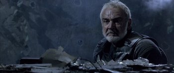 Movie still from “The Rock” (1996), directed by Michael Bay – An older man sitting in front of a pile of papers; Close Up shot, Low angle