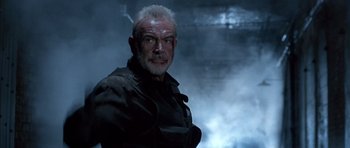 Movie still from “The Rock” (1996), directed by Michael Bay – An older man in a black jacket is looking at the camera; Close Up shot, Low angle