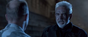 Movie still from “The Rock” (1996), directed by Michael Bay – A man with white hair and a beard talking to another man in a black shirt; Close Up shot, Over the shoulder angle