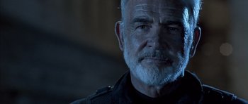 Movie still from “The Rock” (1996), directed by Michael Bay – An older man with a gray beard stares at the camera; Close Up shot, Over the shoulder angle