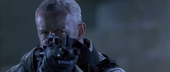 Movie still from “The Rock” (1996), directed by Michael Bay – A person holding a gun; Close Up shot, Over the shoulder angle