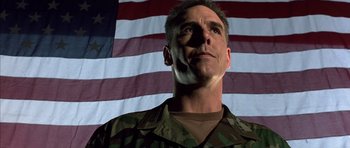 Movie still from “The Rock” (1996), directed by Michael Bay – A man standing in front of an american flag; Close Up shot, Low angle