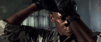 Movie still from “The Rock” (1996), directed by Michael Bay – A man in camouflage is holding a cell phone up to his face; Close Up shot, Low angle