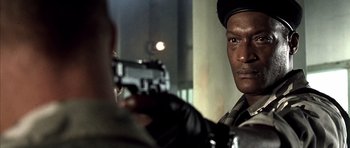 Movie still from “The Rock” (1996), directed by Michael Bay – A man holding a gun in front of another man; Close Up shot, Over the shoulder angle