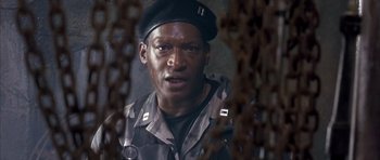 Movie still from “The Rock” (1996), directed by Michael Bay – A man wearing a black hat and a camouflage jacket; Close Up shot, Low angle