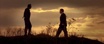 Movie still from “The Rock” (1996), directed by Michael Bay – Two people are walking in a field at sunset; Extreme Wide shot, Low angle