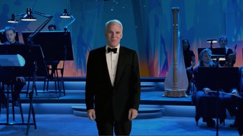 Movie still from “Fantasia 2000” (1999), directed by Eric Goldberg – A man in a tuxedo standing in front of musical instruments; Wide shot, High angle