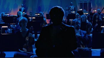 Movie still from “Fantasia 2000” (1999), directed by Eric Goldberg – A group of people sitting in a dark room; Wide shot, Over the shoulder angle