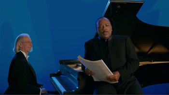 Movie still from “Fantasia 2000” (1999), directed by Eric Goldberg – A man sitting in front of a piano holding a sheet of paper; Medium shot, High angle