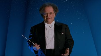 Movie still from “Fantasia 2000” (1999), directed by Eric Goldberg – A man in a tuxedo holding a conductor's baton; Medium shot, Low angle