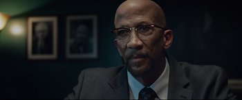Movie still from “Fantastic Four” (2015), directed by Josh Trank – A bald man wearing glasses and a suit; Close Up shot, Over the shoulder angle