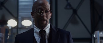Movie still from “Fantastic Four” (2015), directed by Josh Trank – A bald man in a suit and glasses; Close Up shot, Over the shoulder angle