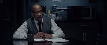 Movie still from “Fantastic Four” (2015), directed by Josh Trank – A man sitting at a table in a room; Medium shot, Over the shoulder angle