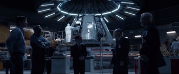 Movie still from “Fantastic Four” (2015), directed by Josh Trank – Two men in suits standing in front of a building; Wide shot, Over the shoulder angle
