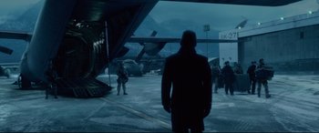Movie still from “Fantastic Four” (2015), directed by Josh Trank – A man standing in front of a plane on a runway; Wide shot, Low angle