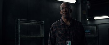 Movie still from “Fantastic Four” (2015), directed by Josh Trank – A man in a plaid shirt standing in a room; Medium shot, Over the shoulder angle