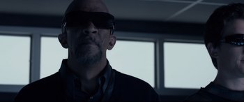 Movie still from “Fantastic Four” (2015), directed by Josh Trank – A man wearing a pair of sunglasses and a black shirt; Close Up shot, Low angle