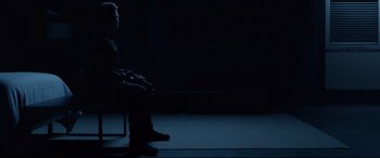 Movie still from “Fantastic Four” (2015), directed by Josh Trank – A man sitting on a chair in a dark room; Wide shot, Over the shoulder angle