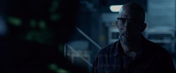 Movie still from “Fantastic Four” (2015), directed by Josh Trank – A bald man with glasses is standing in a dark room; Close Up shot, Over the shoulder angle