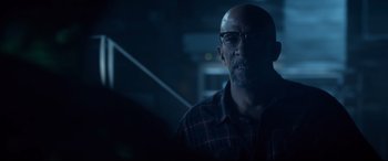 Movie still from “Fantastic Four” (2015), directed by Josh Trank – A man with glasses is looking at the camera in a dark room; Close Up shot, Over the shoulder angle